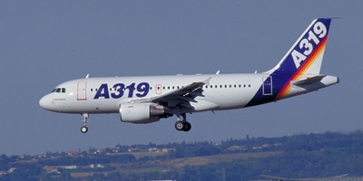 Airbus A319 aircraft flying over a city.