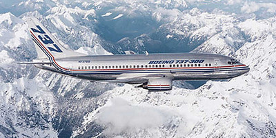 Boeing 737-300 aircraft flying above snow-covered mountains.