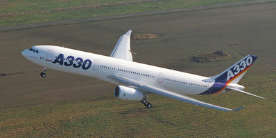 Malaysia Airlines' Airbus A330 aircraft flying over a green field.